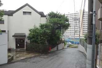 内田さん。昔海だった地にマンションが建つ風景を撮影。雨に濡れた坂の先に、目立つ青いトラックを収めるなど、よく練られた写真です。